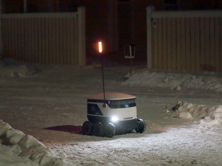 A small white six-wheeled delivery robot on a street in Oulu, Finland